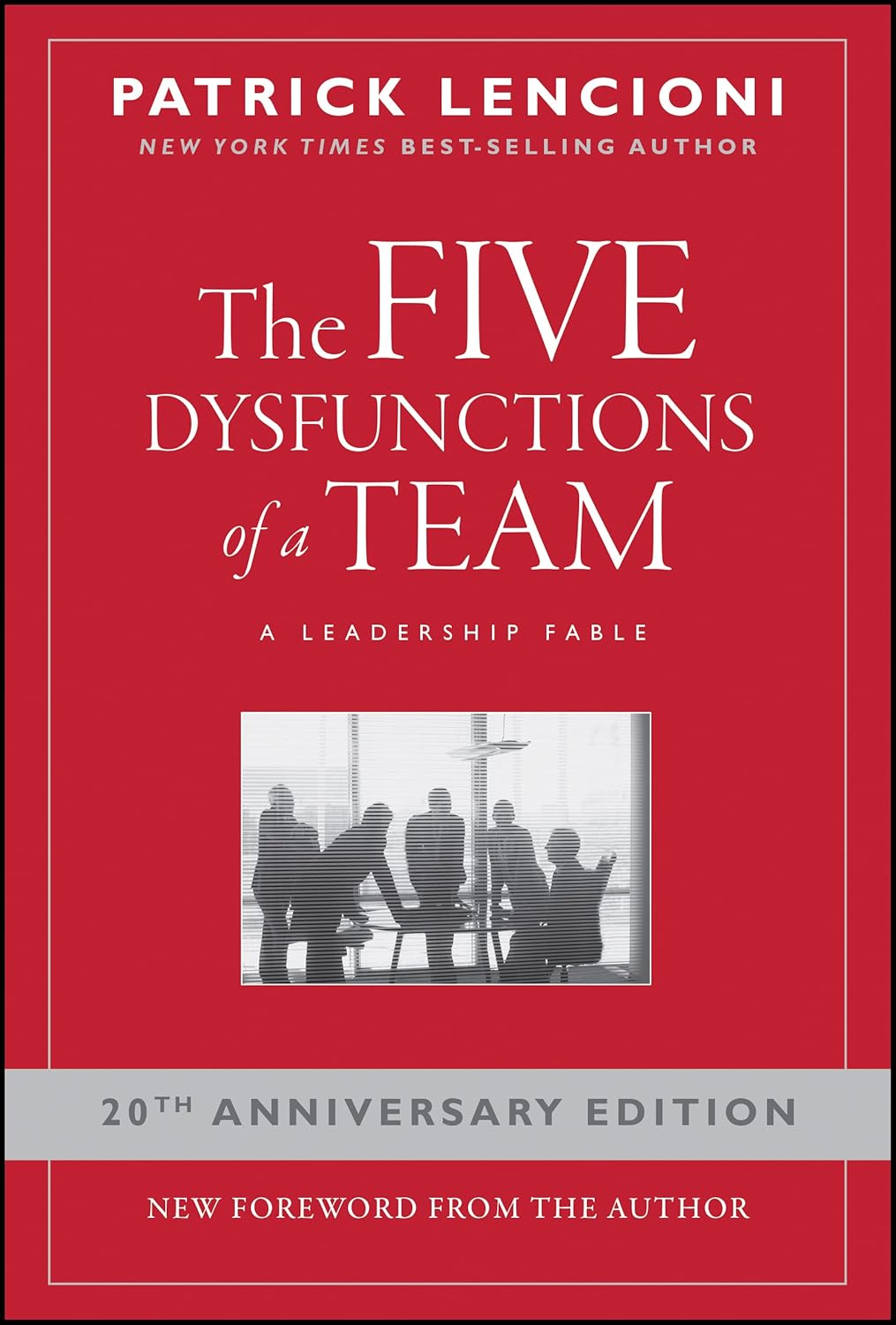 Red cover of The Five Dysfunctions of a Team by Patrick Lencioni, 20th Anniversary Edition, with a grayscale photo of a business meeting.